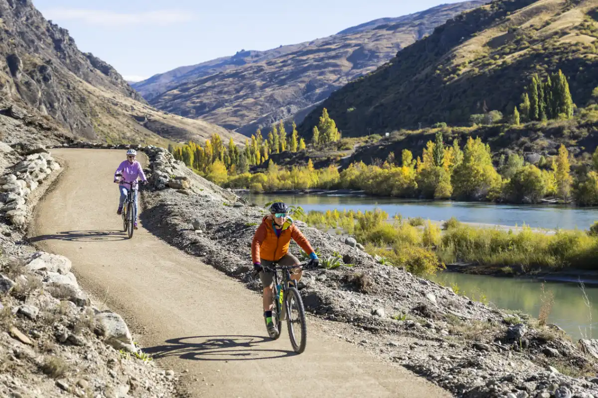Two riders on the trail with the turquoise gorge river below